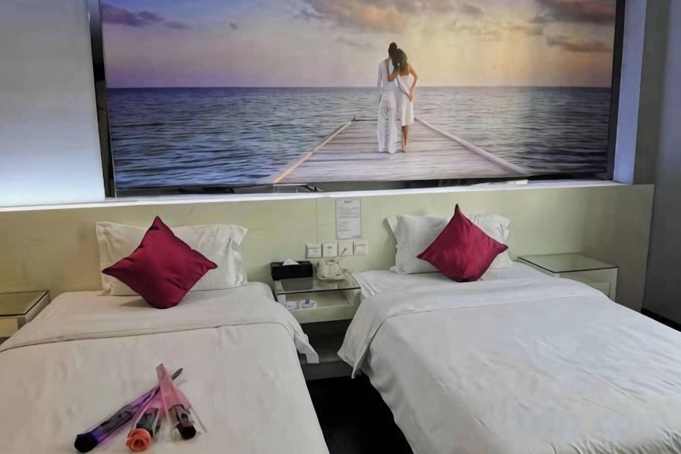 A hotel room with two beds, a large window, and a view of the sea.