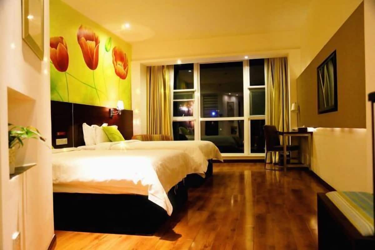 A hotel room with a large bed, a desk, and a view of the city at night.