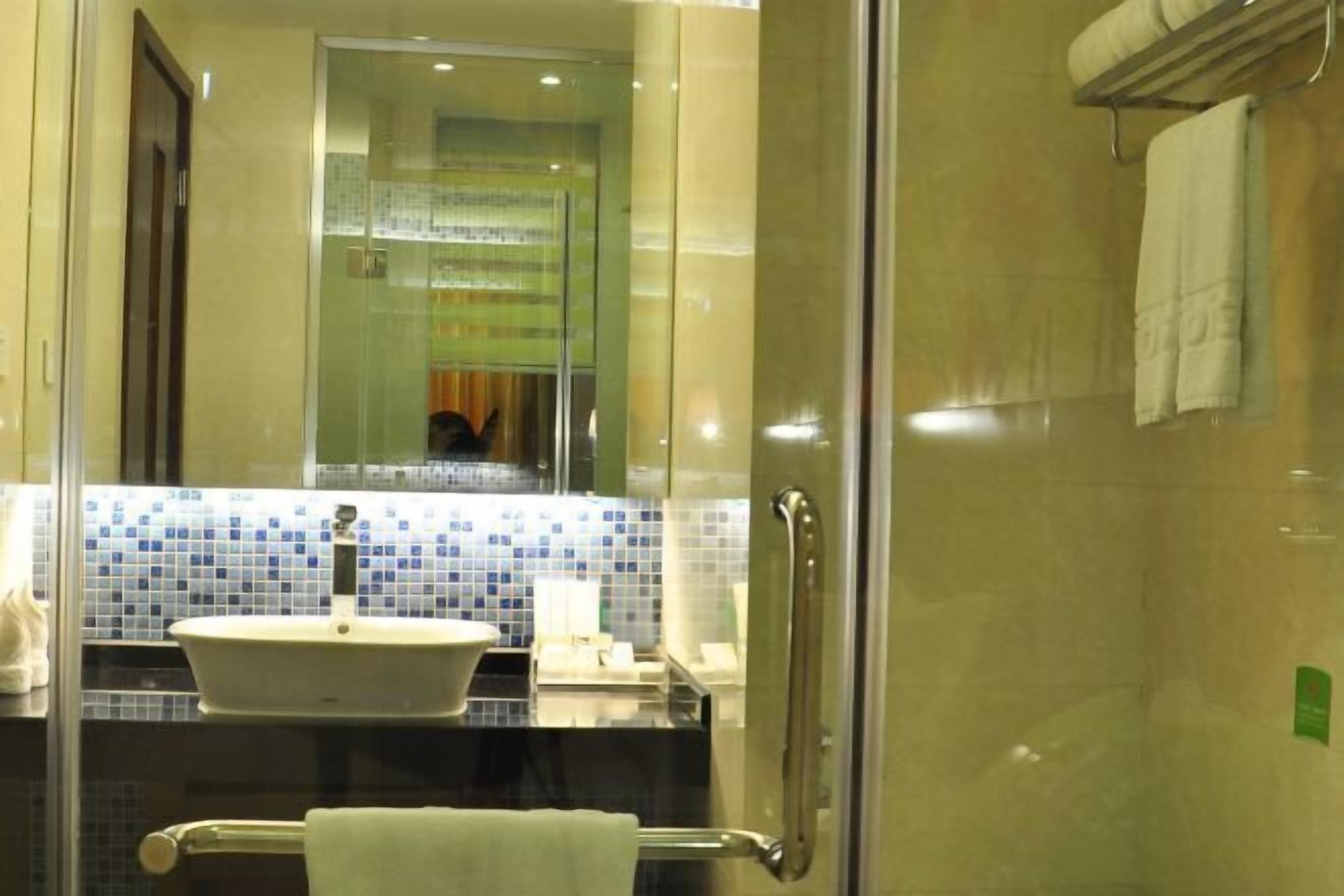 A bathroom with a glass shower enclosure, a sink with a mirror, and a towel rack.
