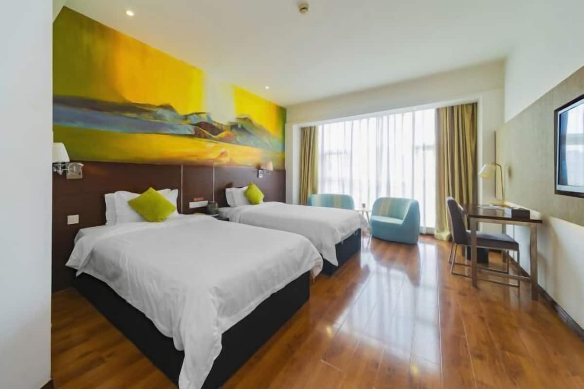A hotel room with two beds, a desk, and a chair.
