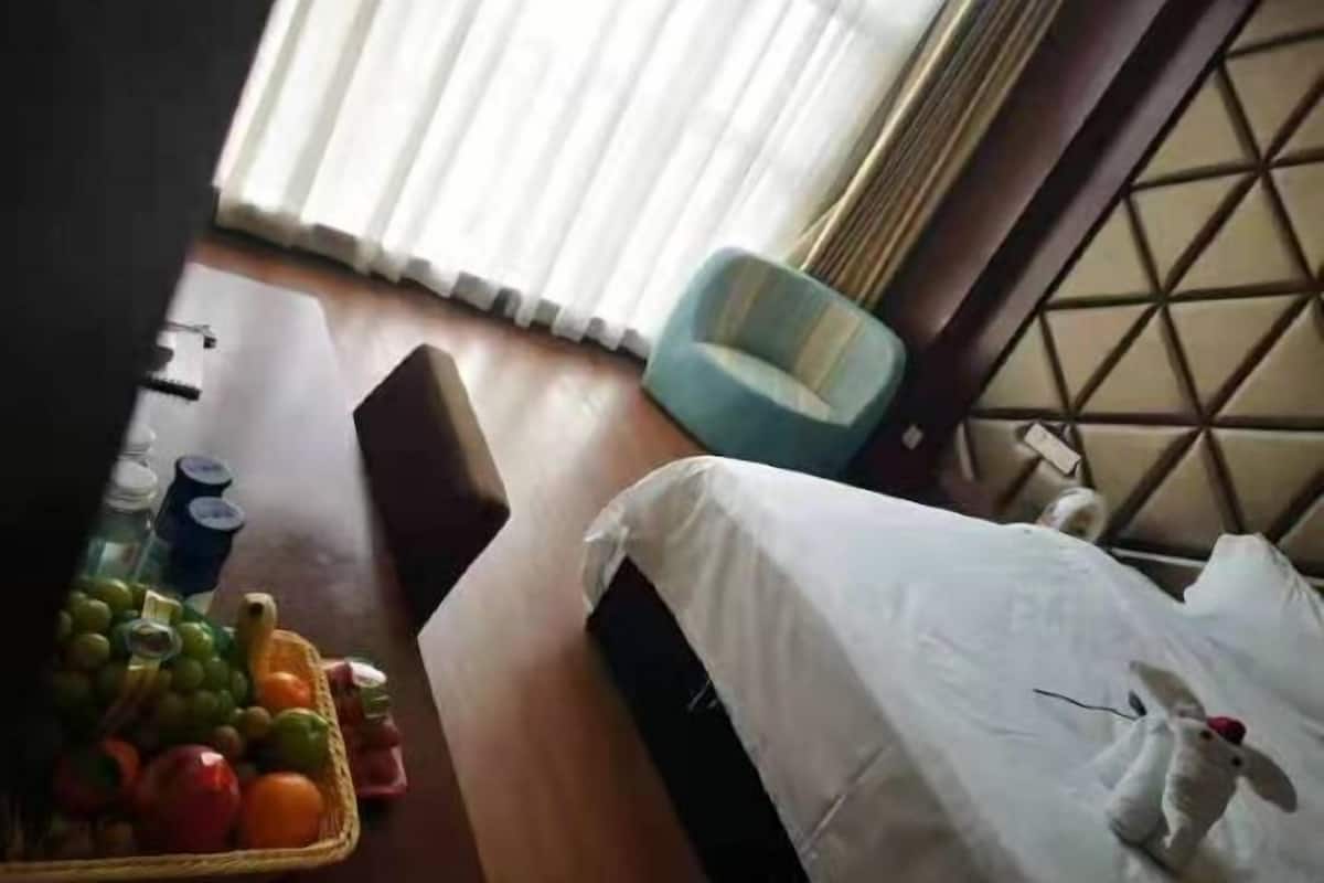 A hotel room with a bed, a chair, and a fruit basket on the table.