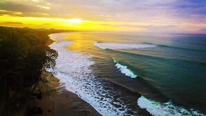 A beach with waves and a sunset.