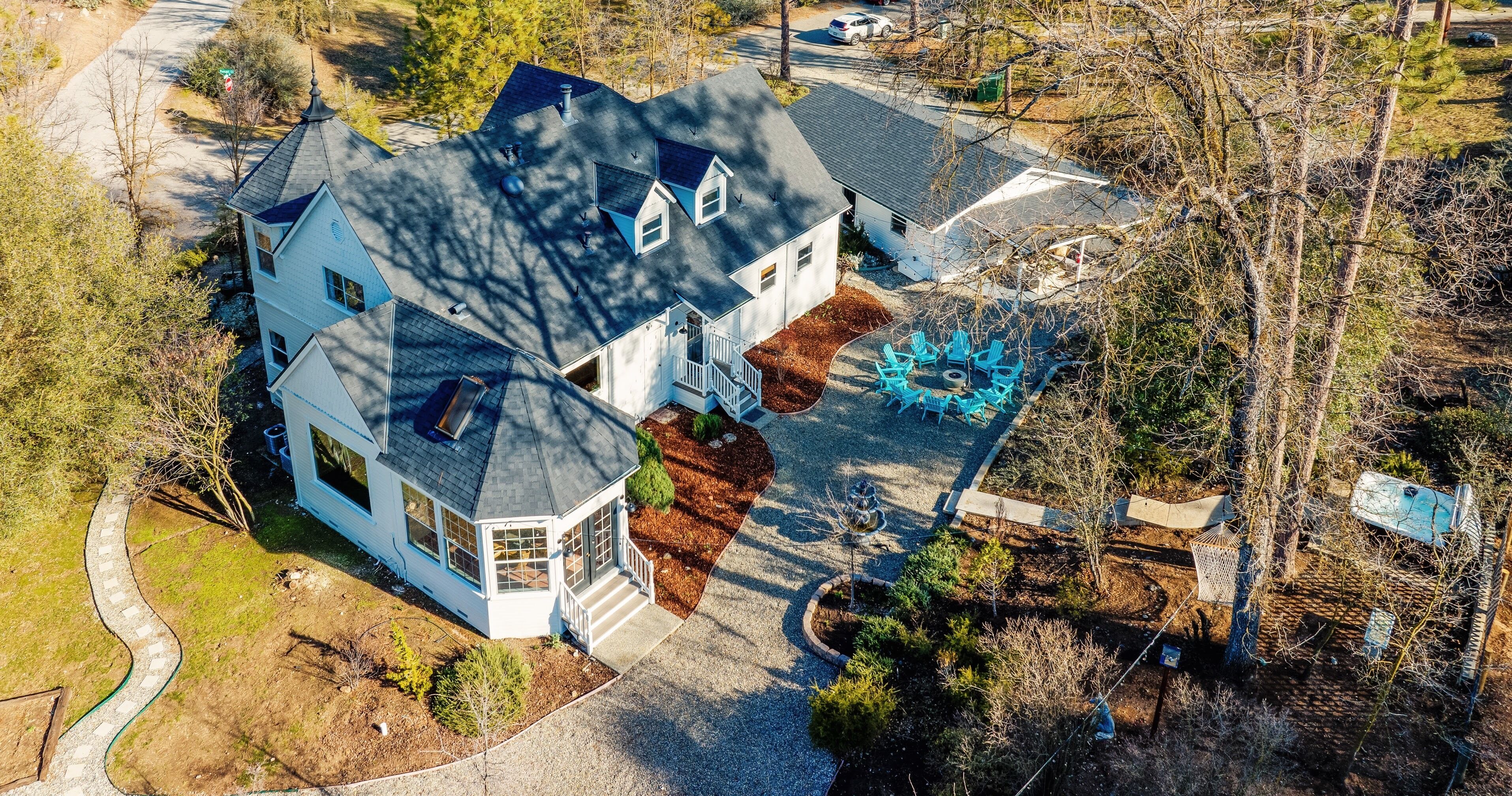 A two-story house with a wrap-around porch, a small attached garage, and a landscaped yard with a patio area.