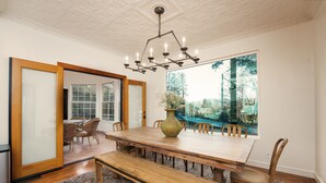 A dining area with a large wooden table, benches, and chairs. There is a large window with a view of trees and a mountain.