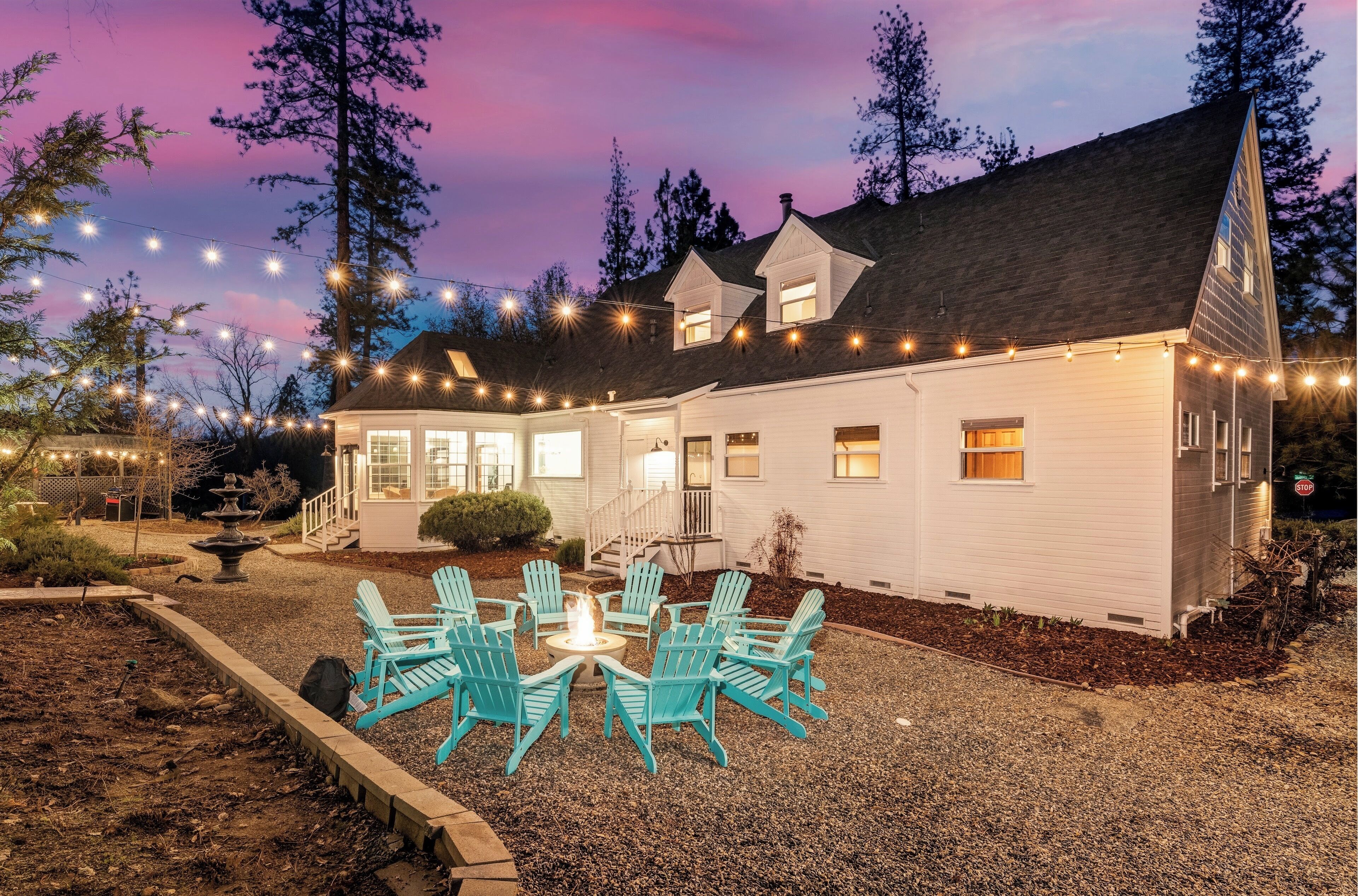A white house with a covered patio, outdoor seating, and string lights.