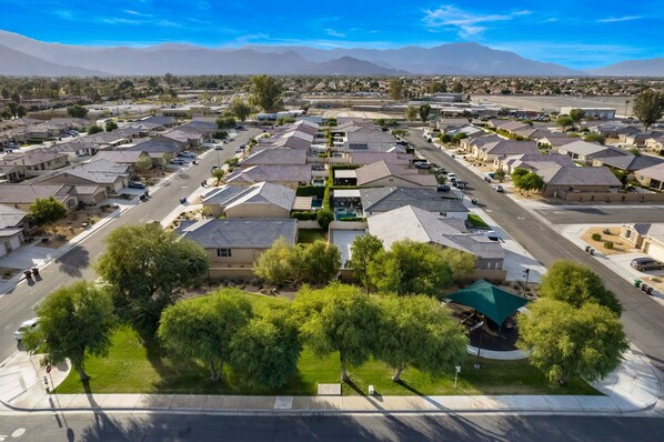Una zona residencial con casas, una avenida central y una cadena montañosa al fondo.