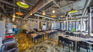 A spacious restaurant with high ceilings, exposed ductwork, and a variety of hanging pendant lights. Tables are arranged in a casual layout, and the floor has a unique, textured pattern. - the allin pension (Gapyeong)