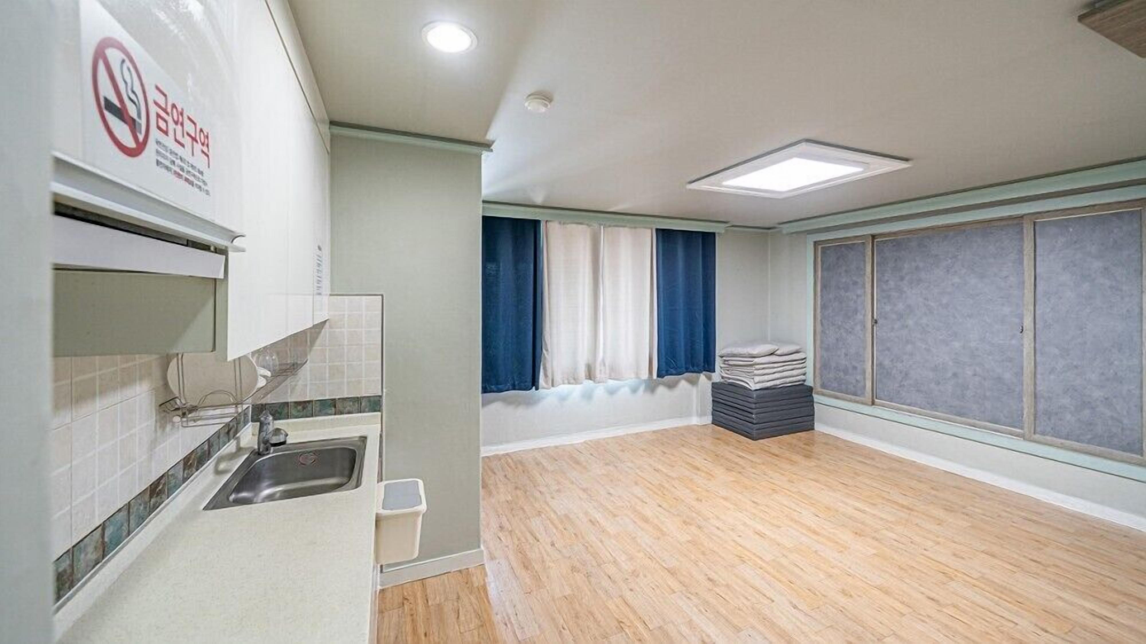 A modern kitchen with a sink, a window with curtains, and a stack of towels.