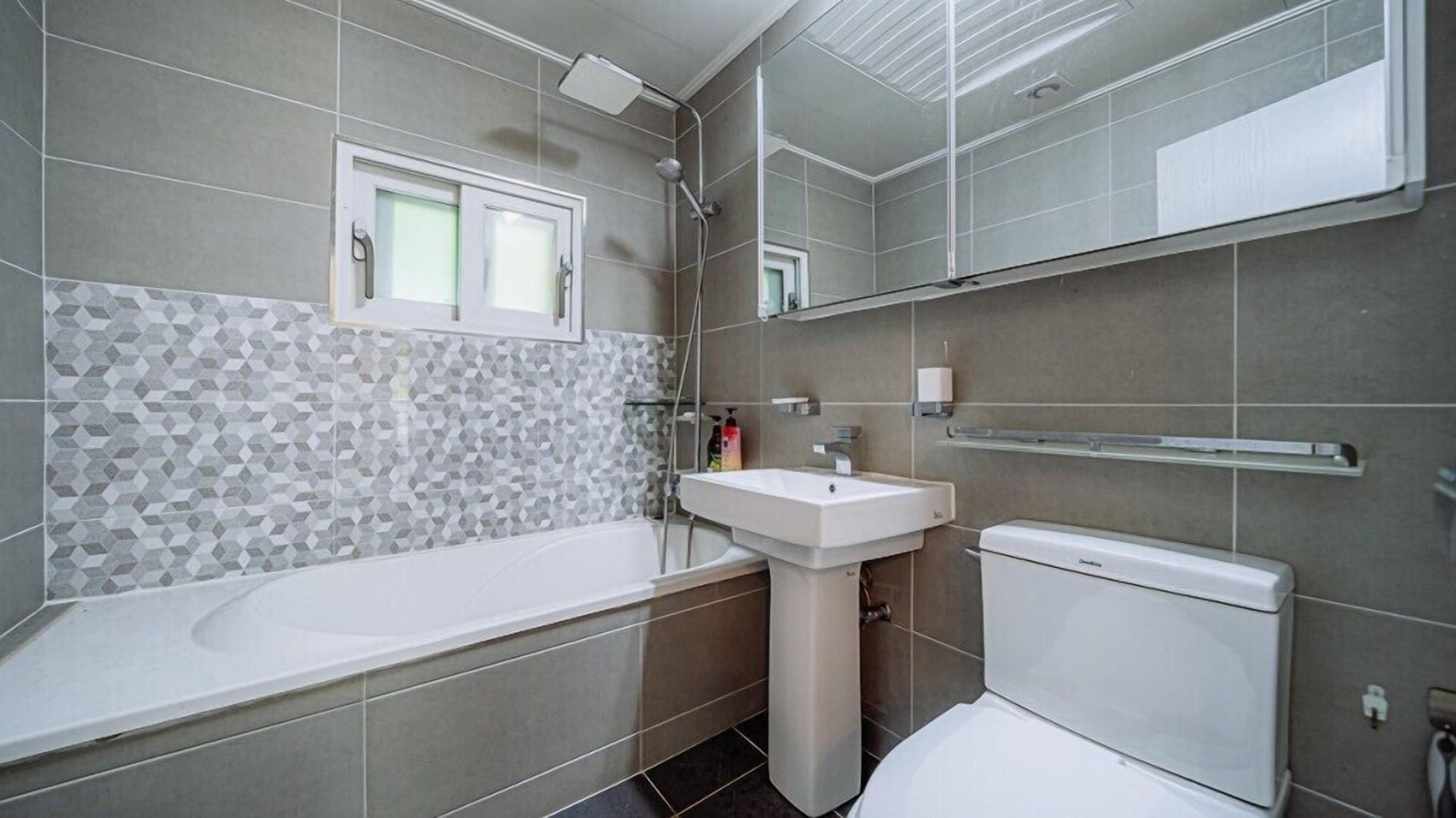 A modern bathroom with a bathtub, a sink, and a toilet.
