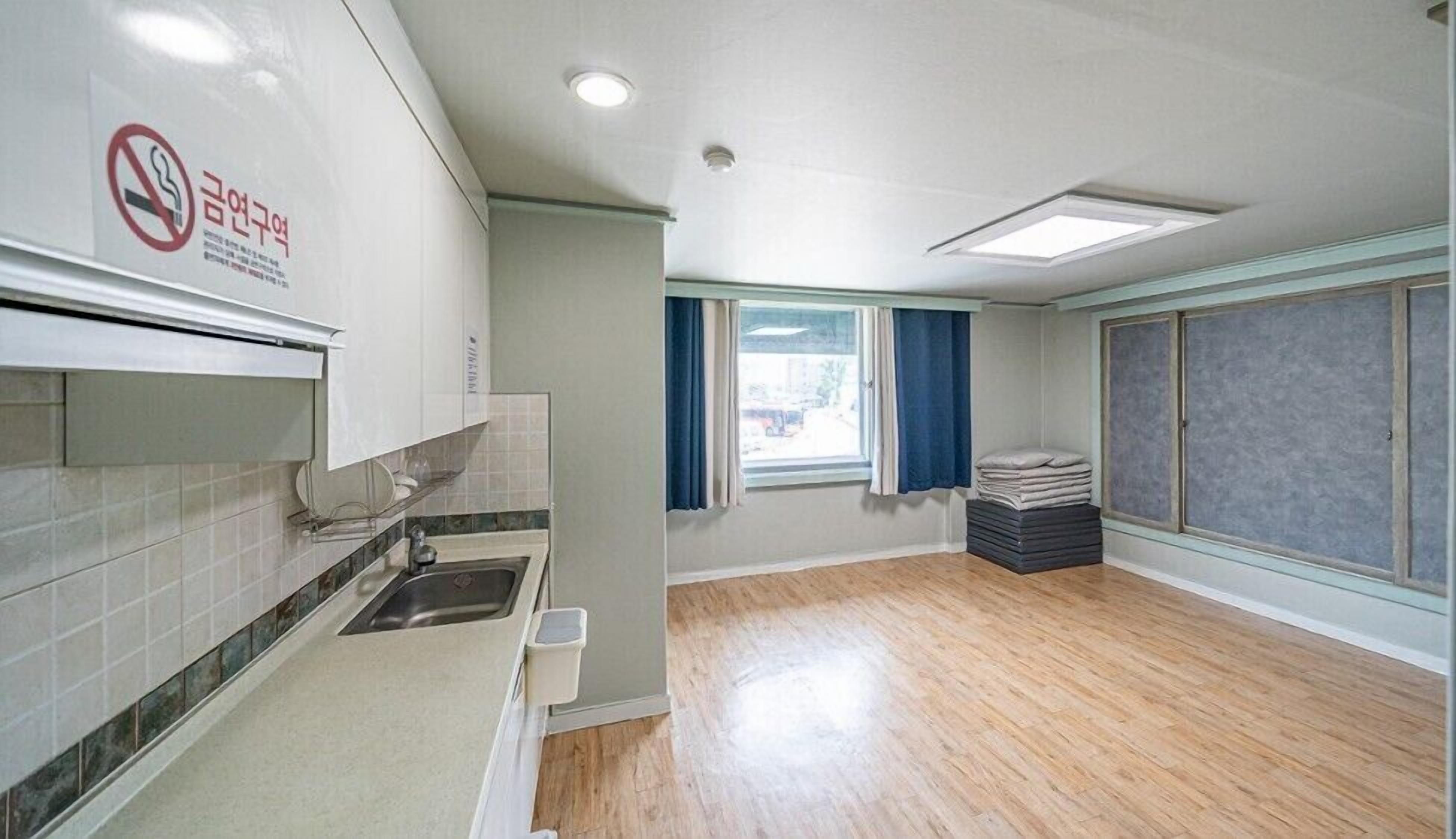 A clean, modern kitchen with a sink, cabinets, and a window with curtains.