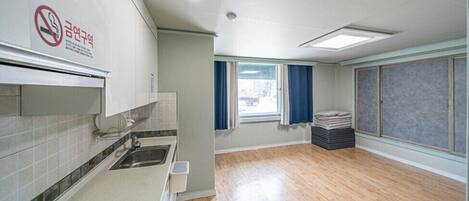 A clean, modern kitchen with a sink, cabinets, and a window with curtains.