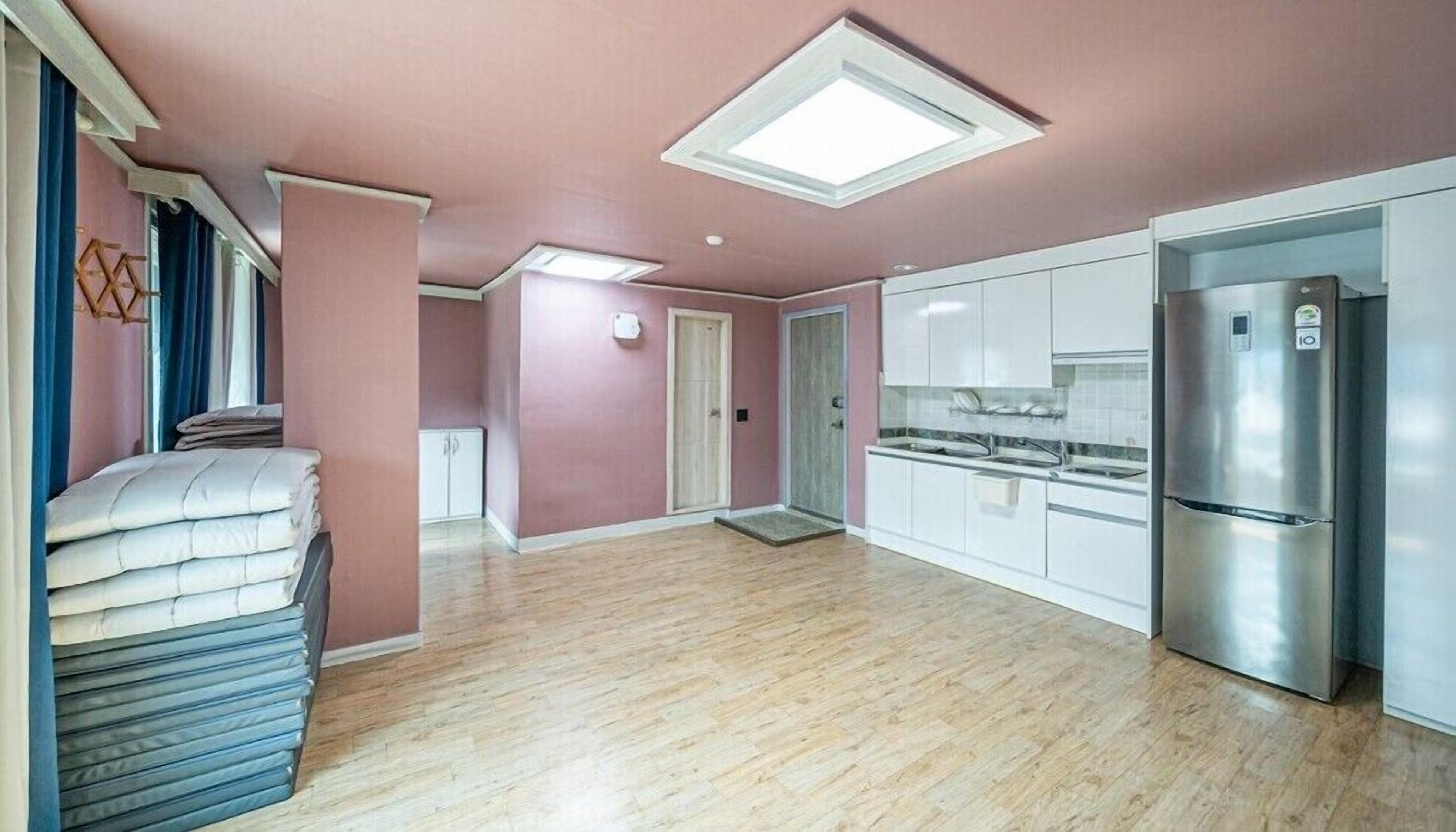 A modern kitchen with white cabinets, a stainless steel refrigerator, and a wooden floor.