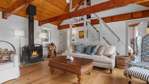 Una sala de estar acogedora con chimenea, vigas de madera, un sofá y un sillón estampado.