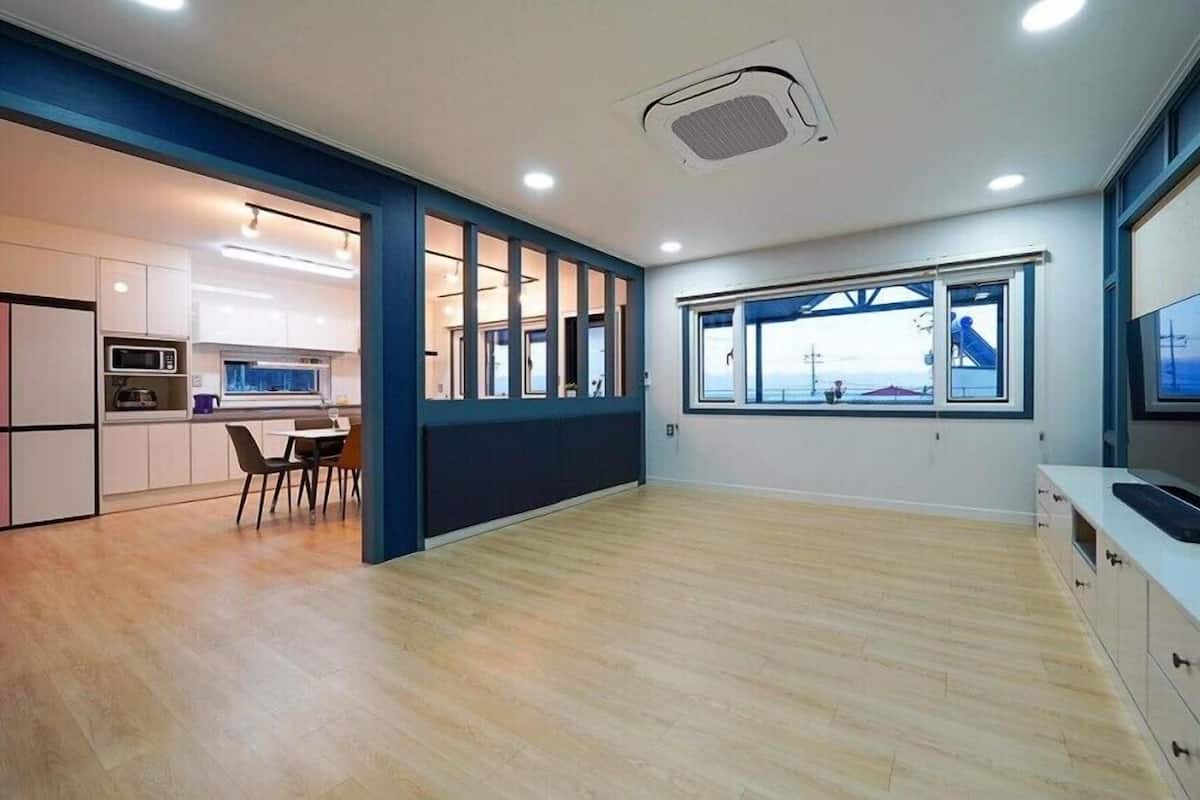 Una habitación moderna y luminosa con zona de cocina, una mesa de comedor y un ventanal con vistas al exterior.
