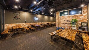 Een restaurant met houten tafels en banken, een bakstenen muur en een bordje met de tekst 'Beach Hill View House'.