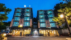 Een hotel met twee verdiepingen, een ster op het dak, grote ramen en een klein entreegebied met zitplaatsen.