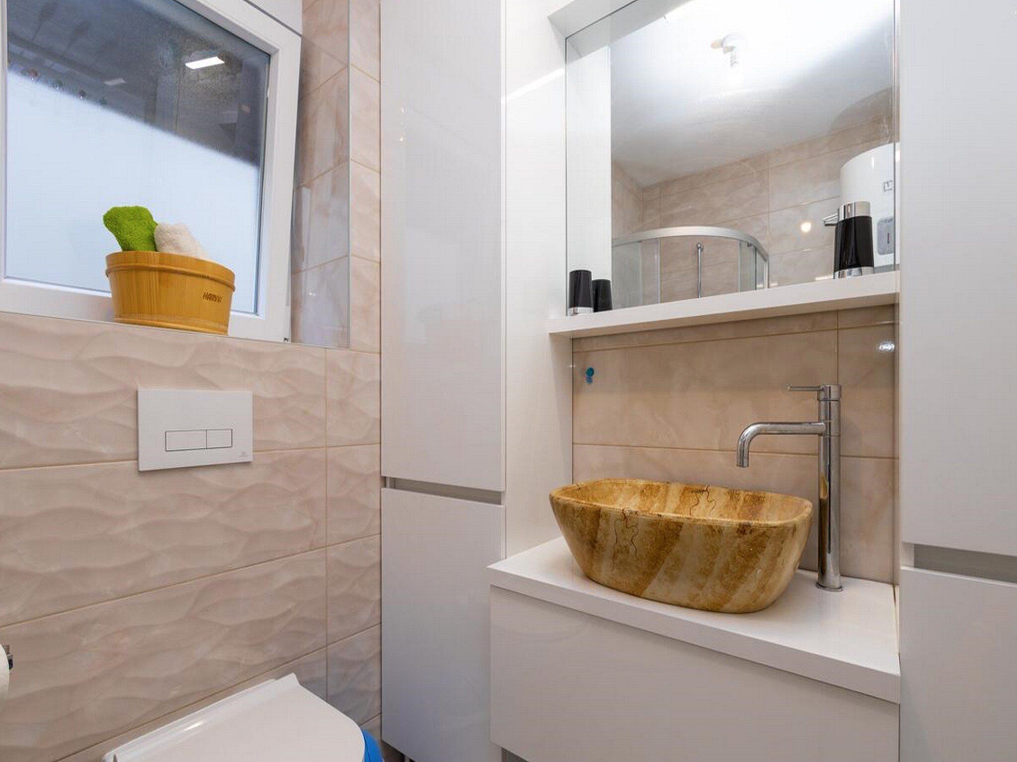 A bathroom with a large window, a sink with a unique bowl design, and a mirror above the sink.