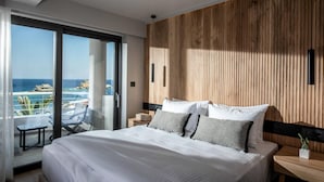 Ein modernes Hotelzimmer mit einem großen Bett, einer Wand als Holzdekor und einem Balkon mit Meerblick.