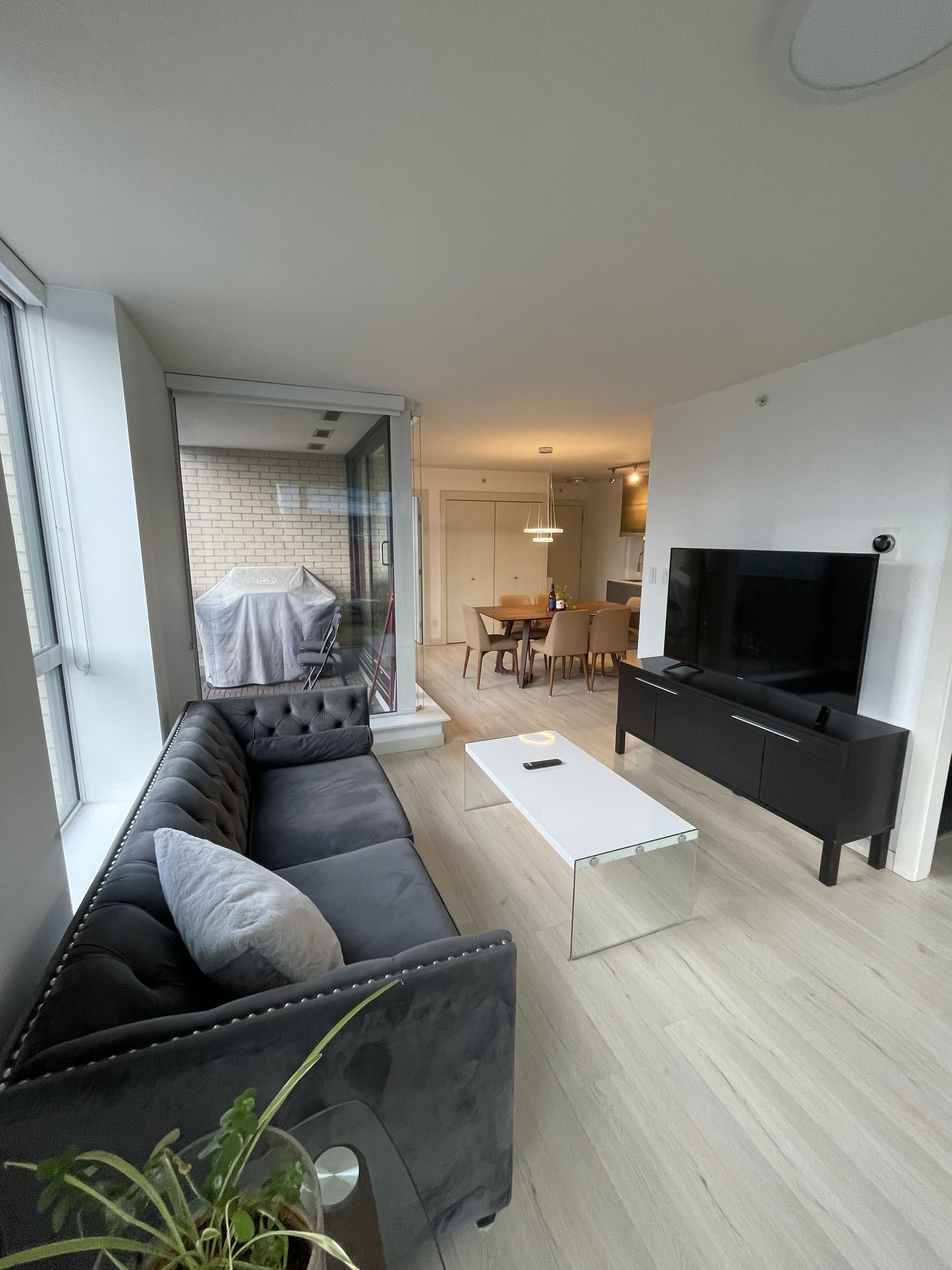 Un salon moderne avec un canapé noir, une table basse blanche et un téléviseur posé sur un meuble noir.