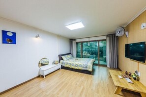 Un dormitorio con cama, mesita de noche, espejo y televisor.