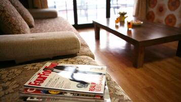 A living room with a sofa, a coffee table, and a stack of magazines.