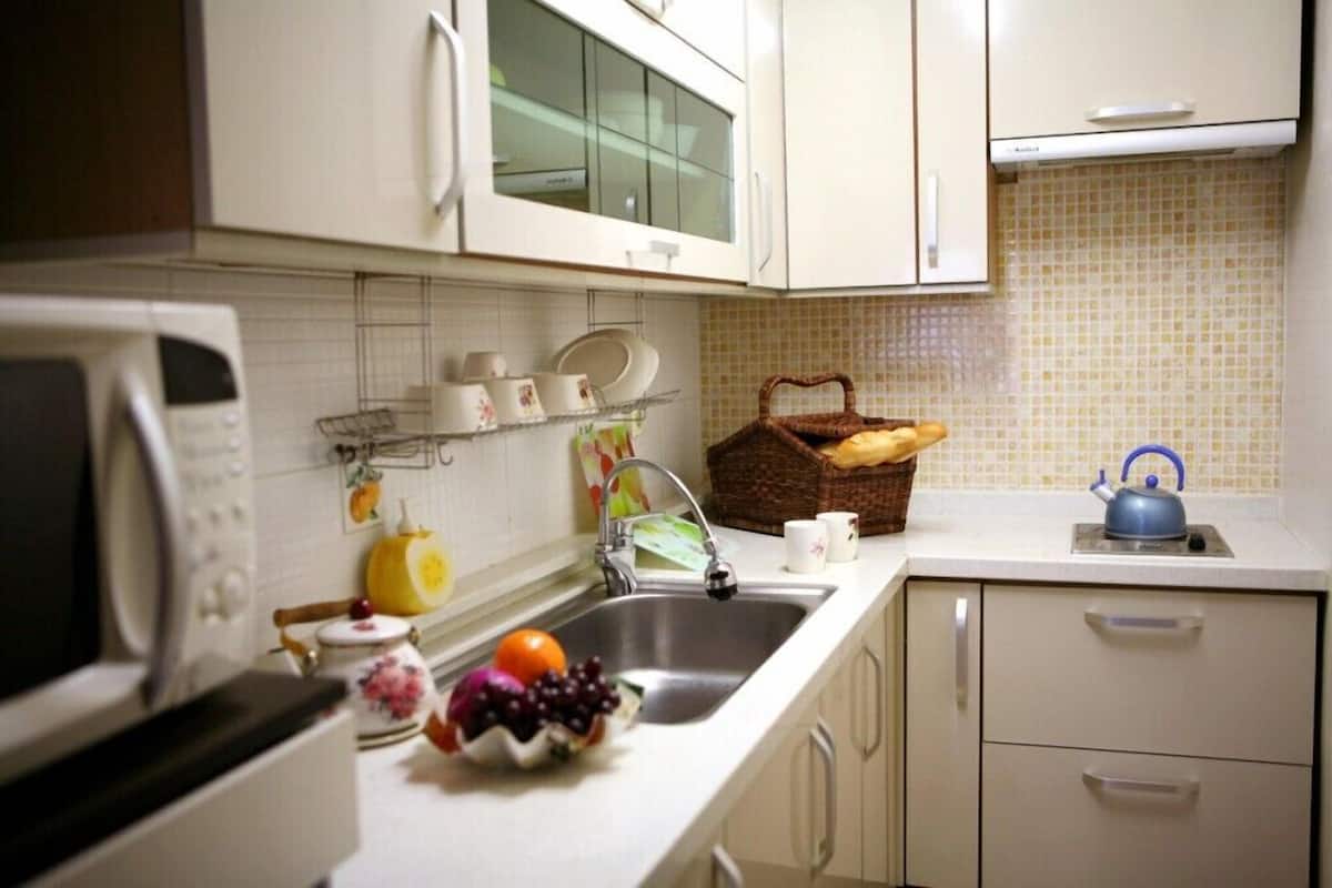 A kitchen with white cabinets, a microwave, a sink, and a basket of bread.