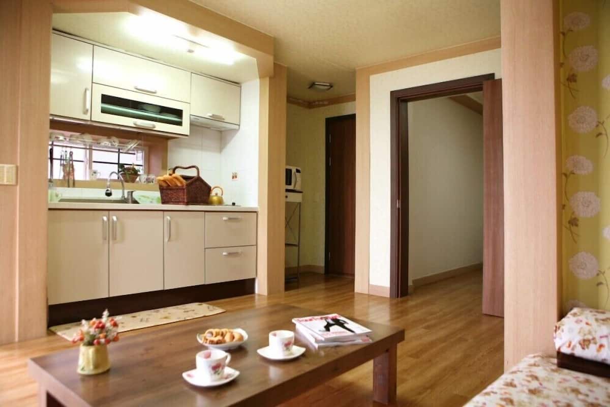 A modern kitchen with white cabinets, a dining table with a vase of flowers, and a microwave in the background.