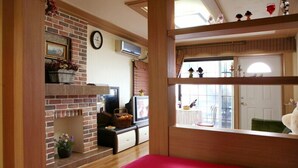 Un salón acogedor con chimenea de ladrillo, televisor y una ventana con adornos.