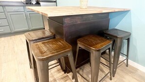 A kitchen with a wooden countertop and three stools with woven seats. - Johnny Cash "The Rambler" Suite on Main - walking distance to all stores and food! (Custer)