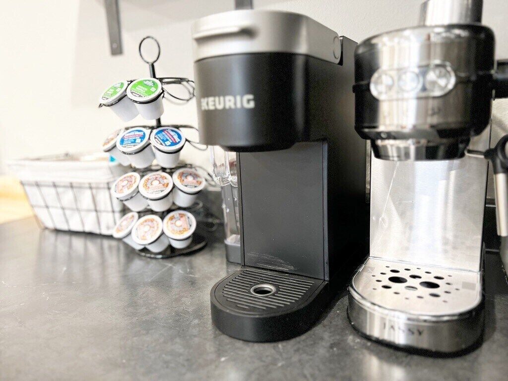 Une machine à café de la marque Keurig, un support pour dosettes de café et une machine à café à filtre.