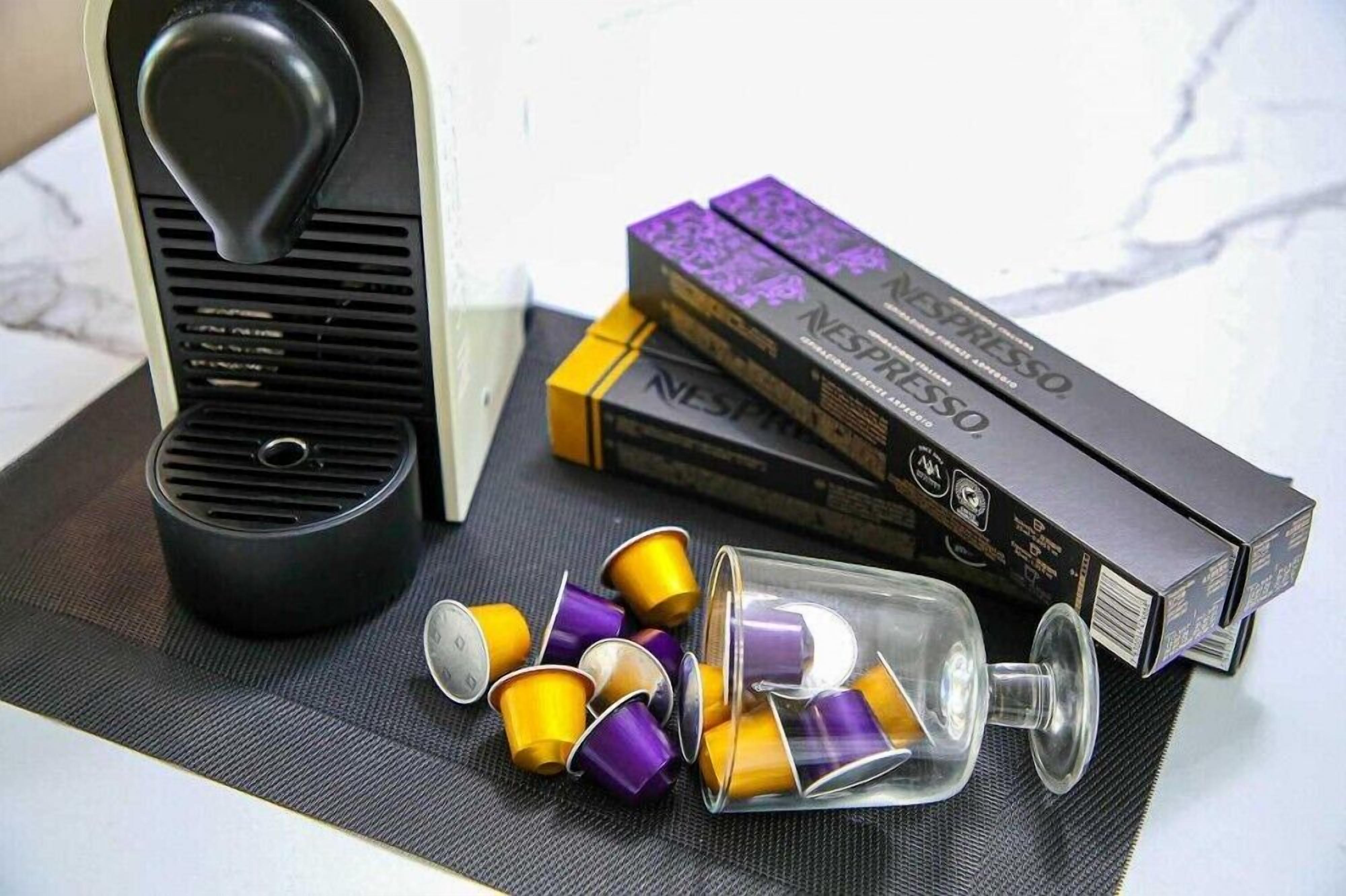 A coffee machine, Nespresso capsules, and boxes on a table.