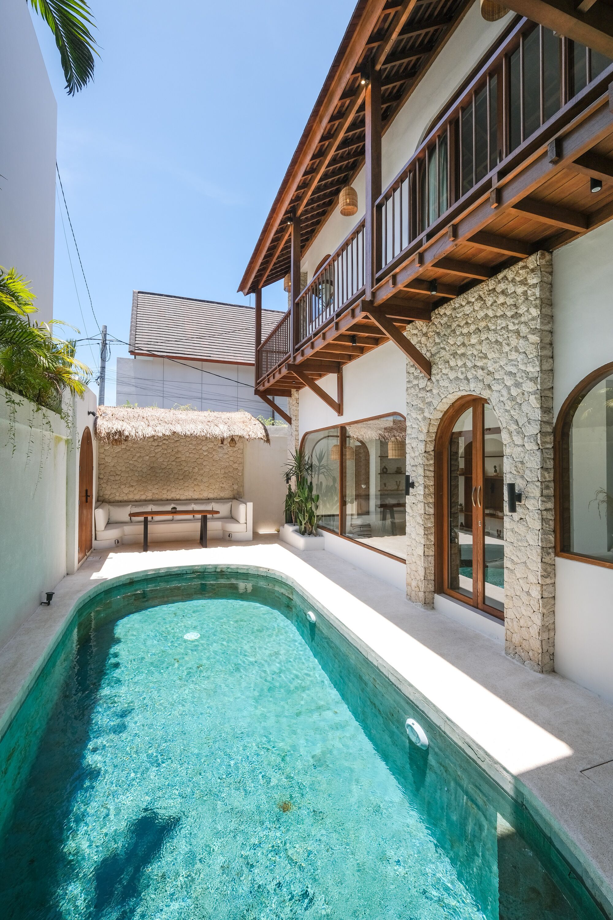 A swimming pool with a stone wall and wooden balcony.