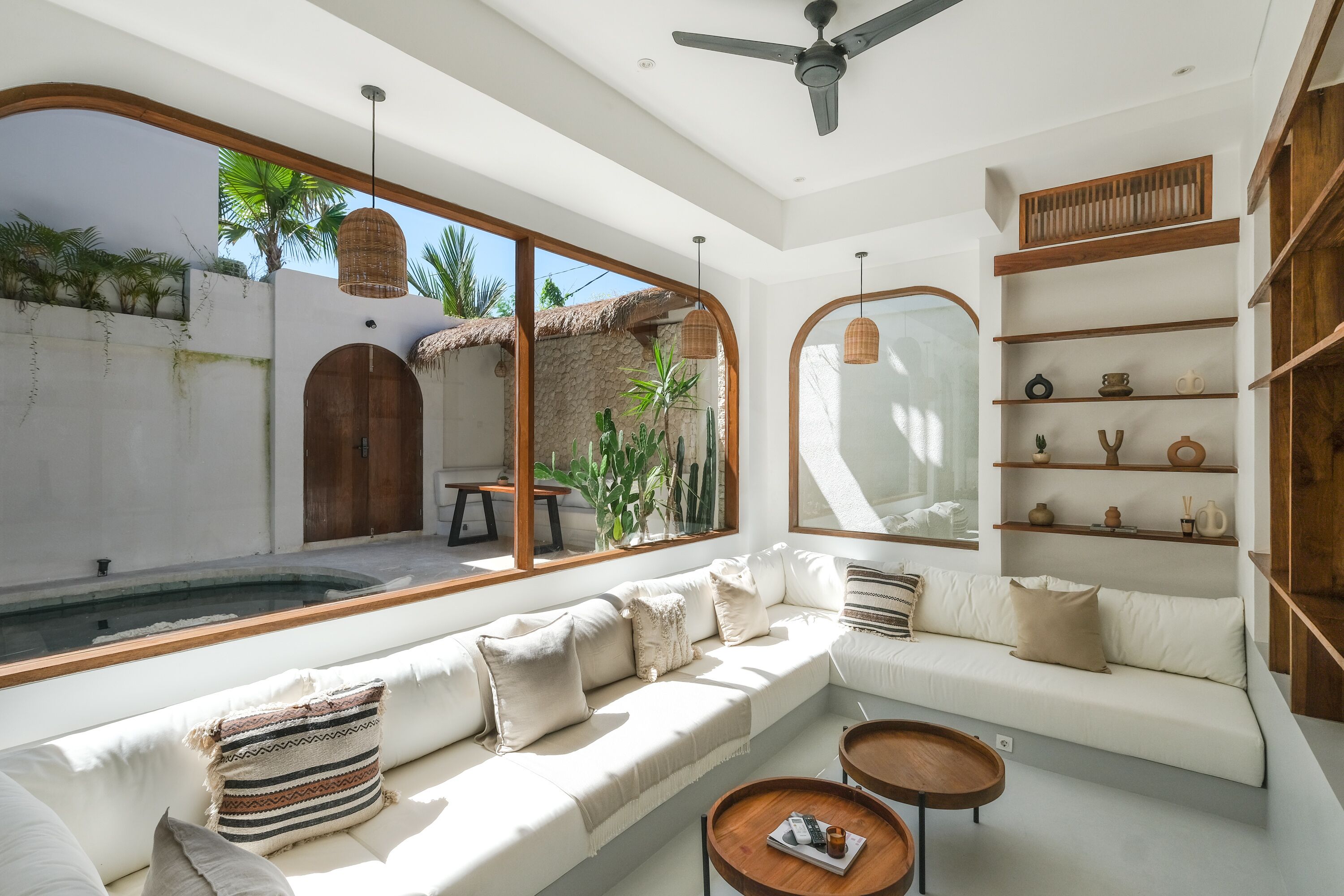 Un soggiorno moderno con una grande finestra, una ventola a soffitto e una libreria a incasso con oggetti decorativi.