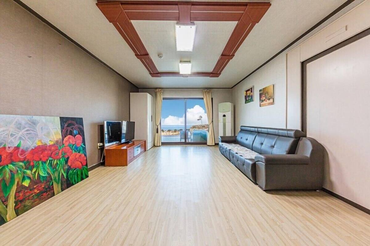 A spacious living room with a large sofa, a flat-screen TV, and a painting on the wall.