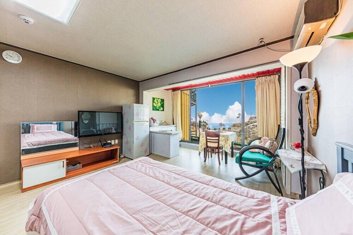 A bedroom with a bed, a TV, a desk, and a chair.