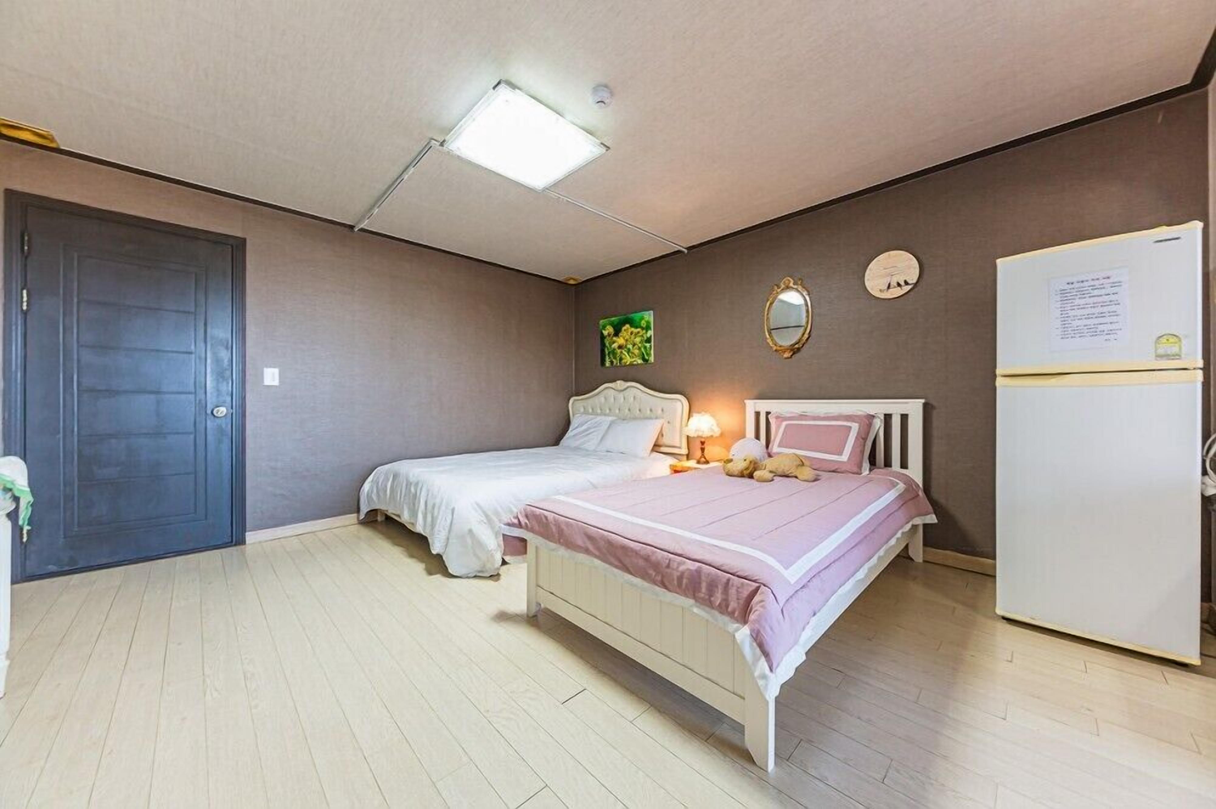 Un dormitorio con dos camas, un armario blanco, una puerta y una lámpara en el techo.