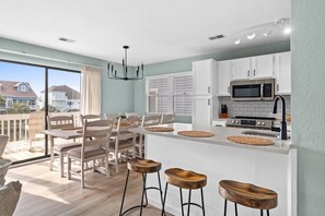 A modern kitchen with white cabinets, a large island, and a view of the outside.