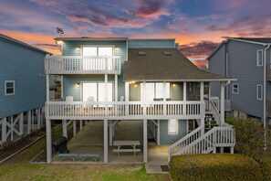 A two-story building with a balcony, outdoor seating, and a staircase.