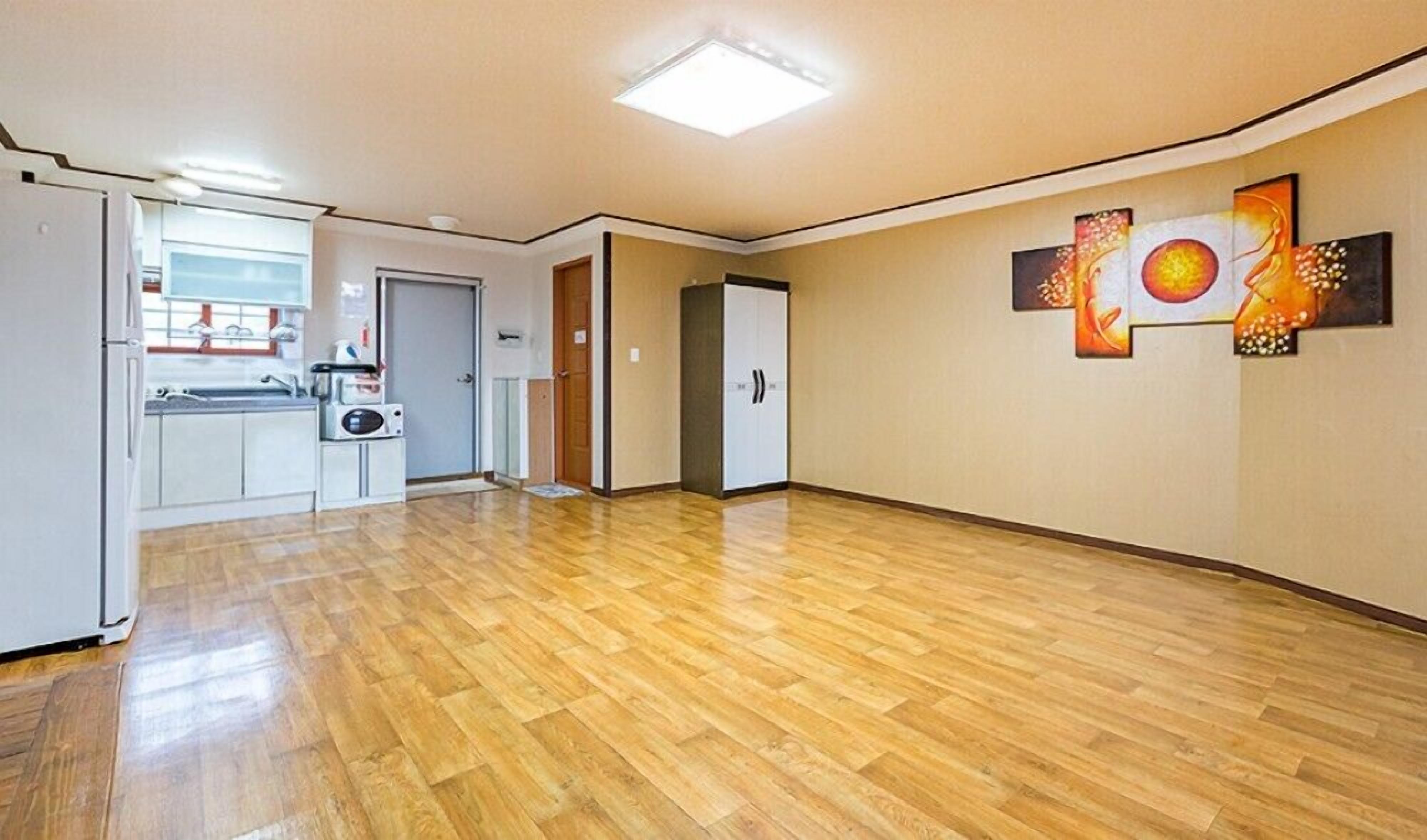 Een ruime woonkamer met een keuken, een deur naar een andere kamer en kunst aan de muur.