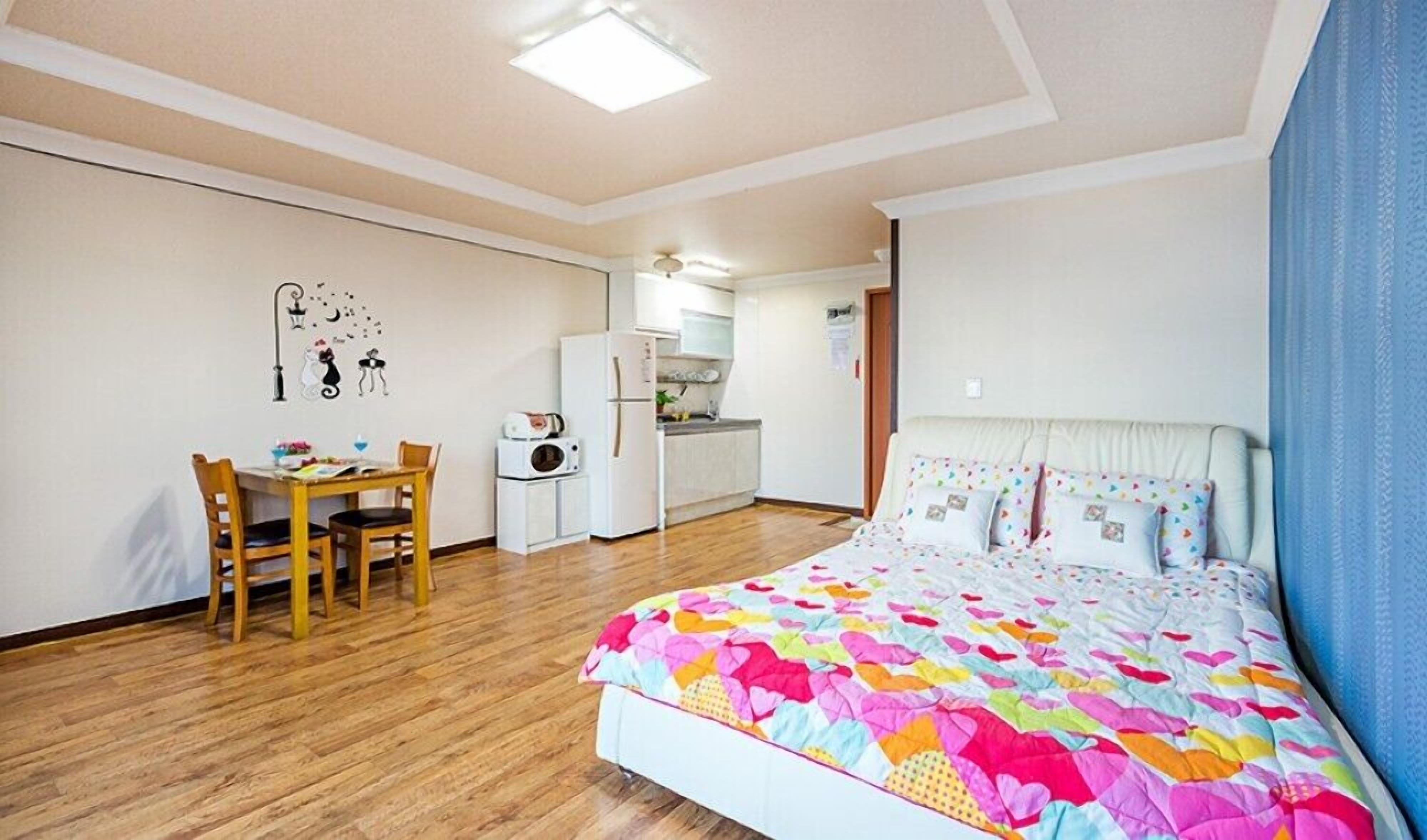 Een slaapkamer met een bed, een bureau en een kitchenette.