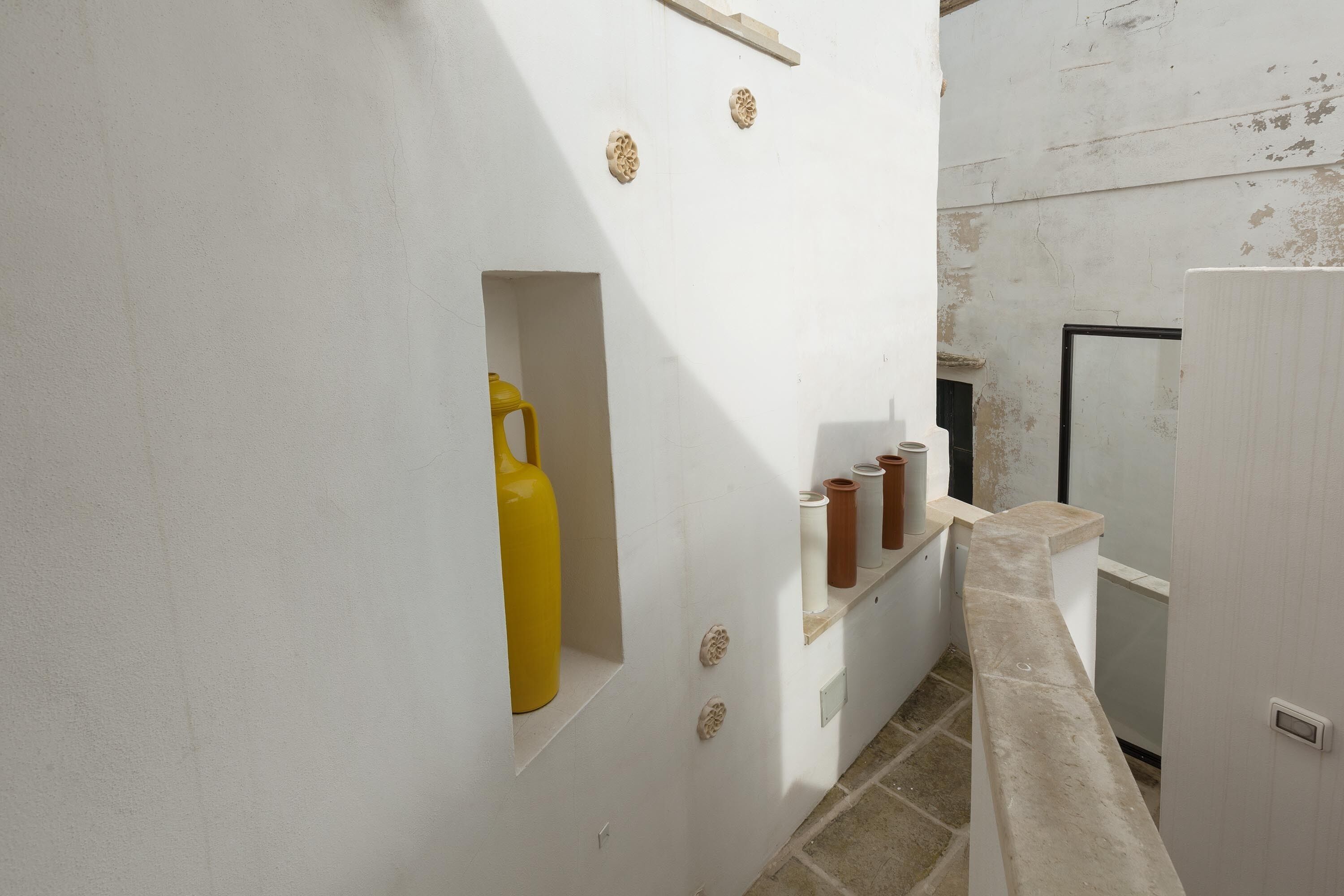A narrow hallway with a white wall, a yellow container, and a white door.