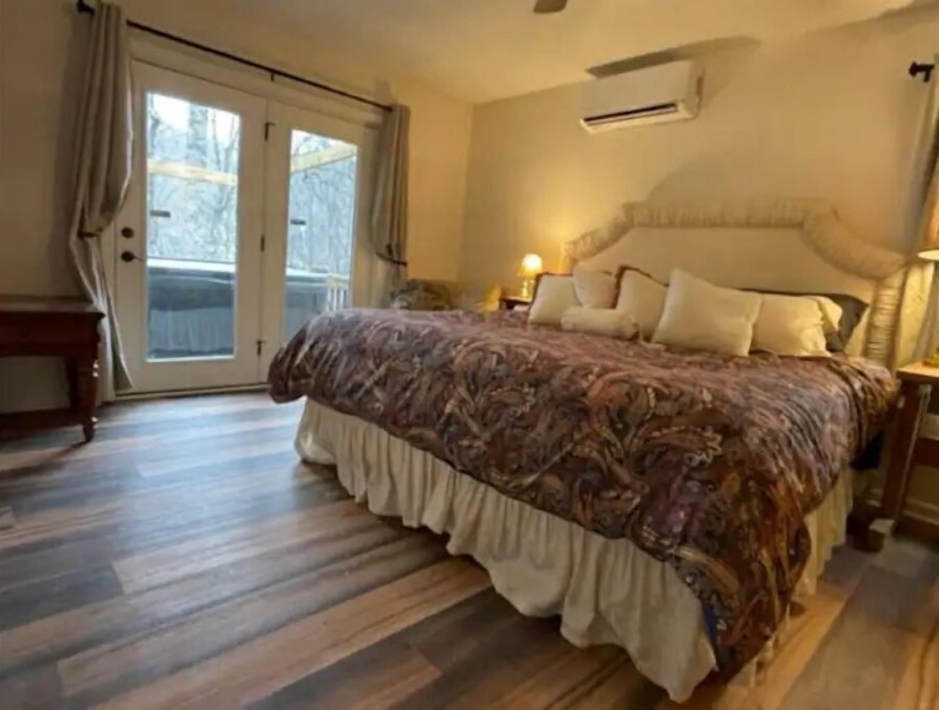Un dormitorio con una cama grande, una puerta corrediza de vidrio y un equipo de aire acondicionado en la pared.