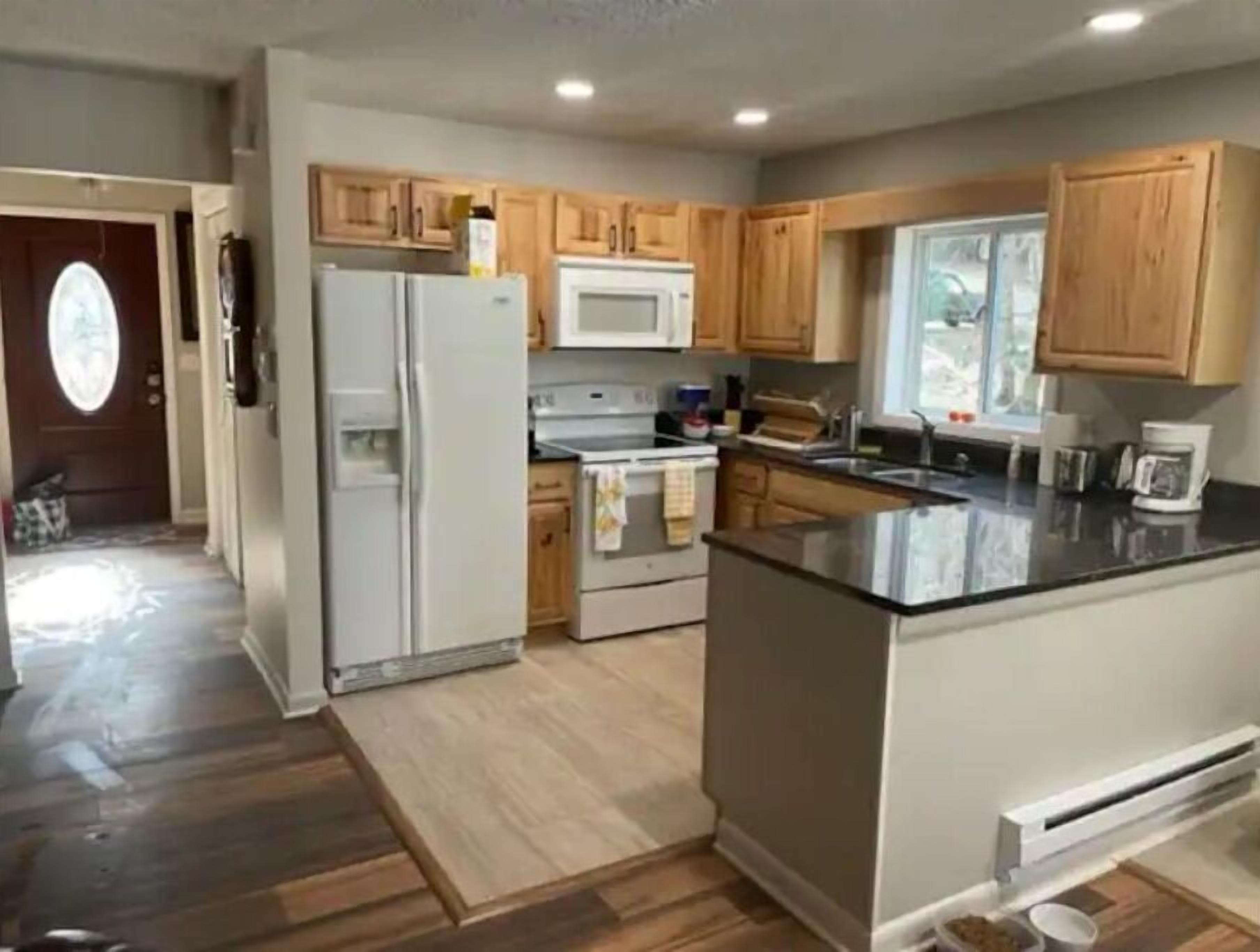 Una cocina moderna con armarios de madera, un refrigerador, un microondas y una estufa.