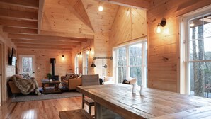 Ein Holzblockhaus-Interieur mit einem großen Esstisch, einer Couch und einem Kamin.