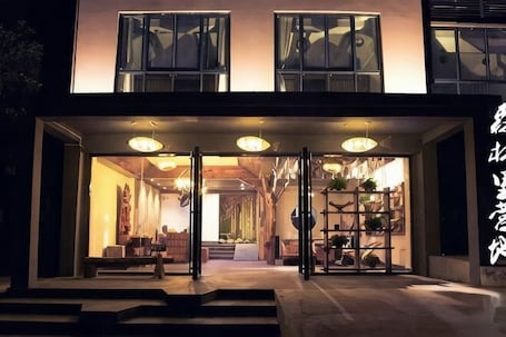 A building with a modern entrance, glass doors, and a staircase leading inside.. Senlinli Campsite