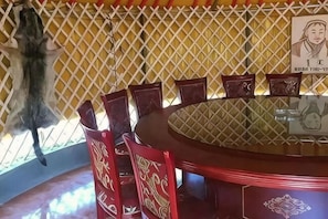 Une table ronde entourée de chaises, un mur orné de motifs et un objet suspendu.