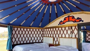 A yurt with a lattice wall, two beds, and a large window.