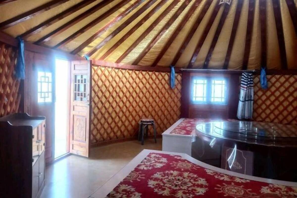 A yurt with a wooden interior, a central table, and a small stool.