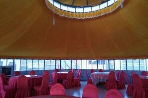 A tented event space with round tables and chairs, large windows, and a circular ceiling design. - Ulan tuya hosts tribes in the helamuren steppe (Damao Banner)