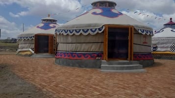 A traditional yurt with a circular structure, a central door, and a small porch.
